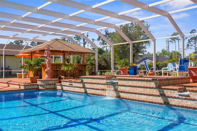 outdoor pool featuring glass enclosure, a patio area, and outdoor dry bar