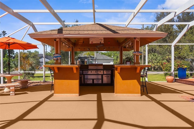 view of patio with a lanai, a grill, and outdoor dry bar