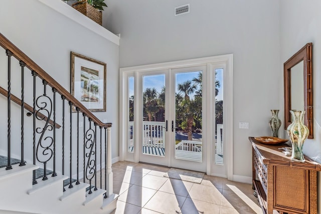 entrance foyer with visible vents, stairway, french doors, a towering ceiling, and light tile patterned flooring