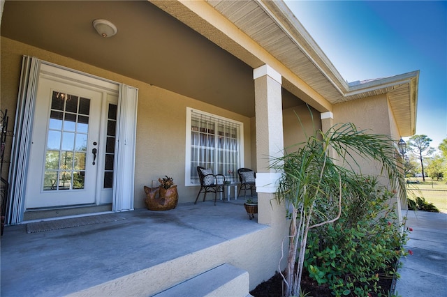 doorway to property with stucco siding and covered porch