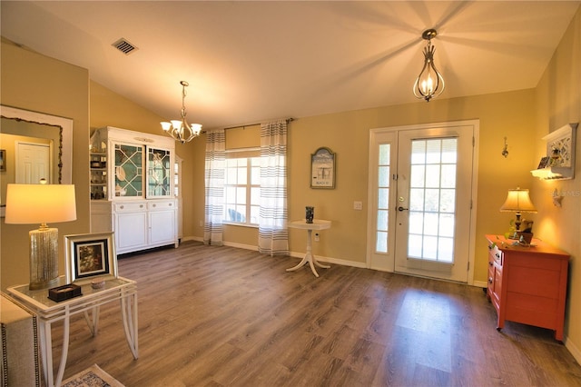 entryway with visible vents, a notable chandelier, wood finished floors, baseboards, and vaulted ceiling