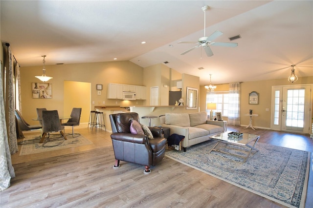 living area with light wood finished floors, visible vents, baseboards, ceiling fan with notable chandelier, and high vaulted ceiling