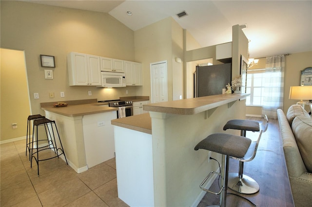 kitchen with light tile patterned floors, visible vents, a breakfast bar, a peninsula, and stainless steel appliances