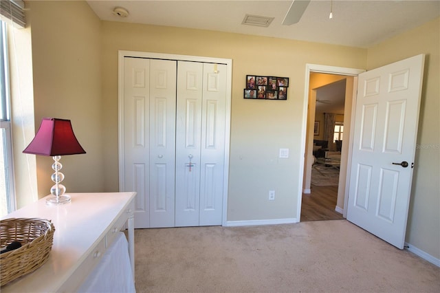 bedroom featuring baseboards, visible vents, light carpet, and a closet