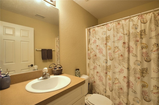 bathroom with visible vents, toilet, vanity, a textured wall, and a textured ceiling