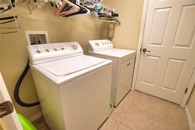 washroom with laundry area, light tile patterned floors, separate washer and dryer, and baseboards