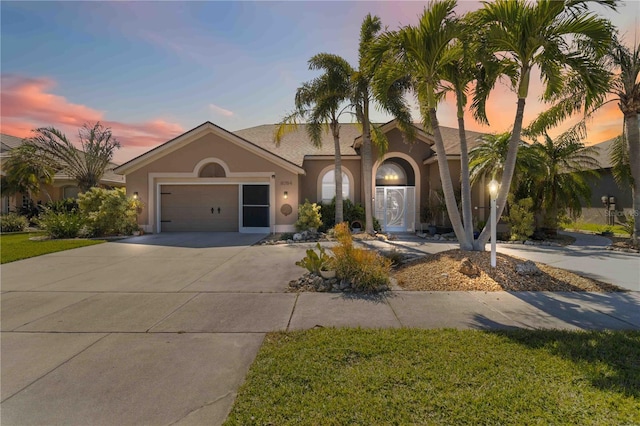 view of front facade featuring an attached garage, driveway, and stucco siding