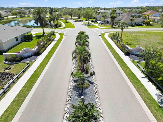 view of street with sidewalks, curbs, a residential view, and a water view