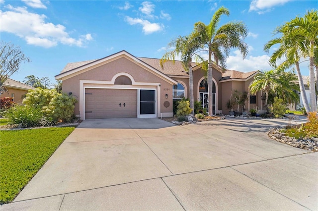 single story home with stucco siding, a front lawn, a garage, and driveway