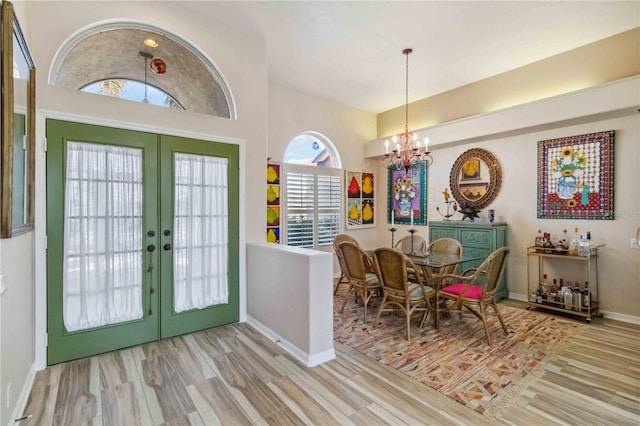 foyer featuring french doors, baseboards, an inviting chandelier, and wood finished floors