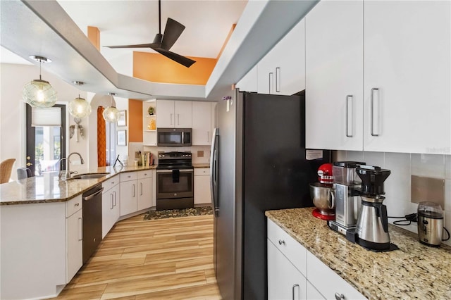 kitchen with ceiling fan, a peninsula, stainless steel appliances, a raised ceiling, and a sink