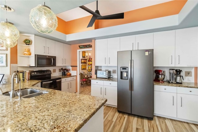 kitchen with a ceiling fan, open shelves, a sink, stainless steel appliances, and a raised ceiling