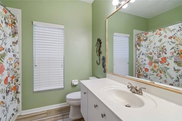 bathroom featuring baseboards, toilet, wood finished floors, and vanity