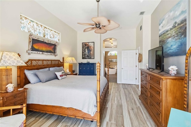 bedroom featuring light wood-type flooring, arched walkways, visible vents, and ceiling fan