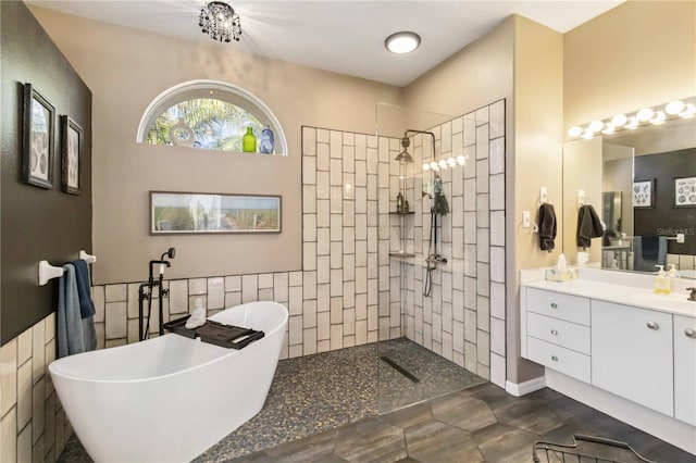 bathroom with a freestanding bath, tile walls, vanity, and a walk in shower