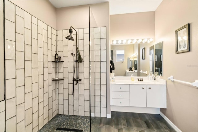 full bath featuring baseboards, wood finished floors, vanity, and a walk in shower