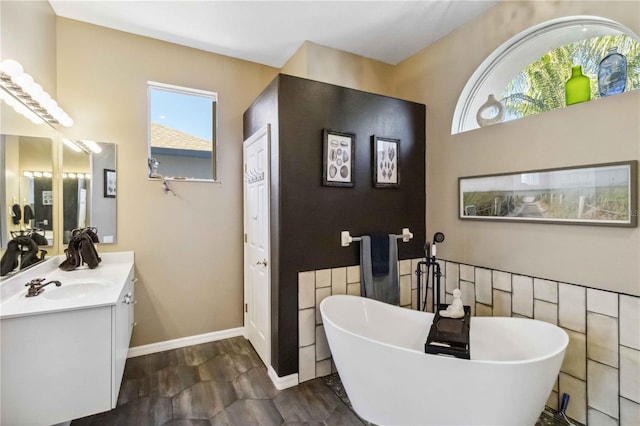 bathroom with vanity, baseboards, and a freestanding bath