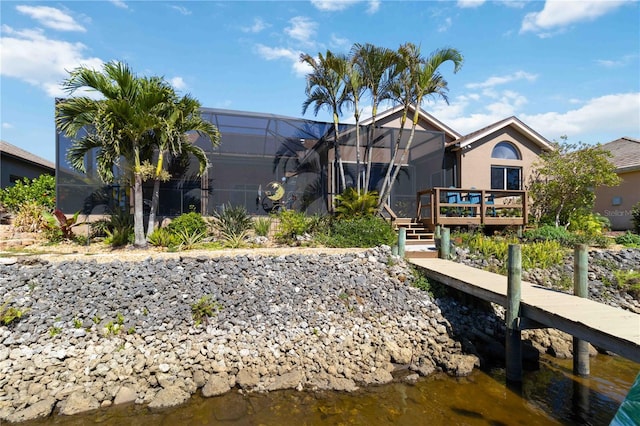 rear view of property featuring a lanai, stucco siding, and a deck with water view