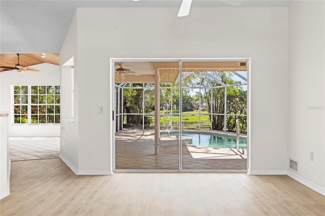 doorway featuring wood finished floors, baseboards, a sunroom, and ceiling fan