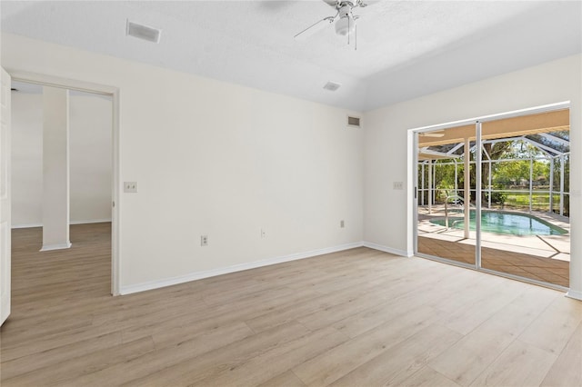 unfurnished room with visible vents, baseboards, a sunroom, ceiling fan, and light wood-style floors