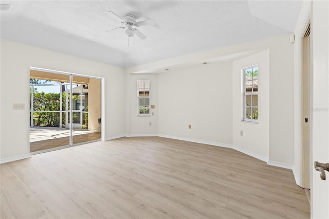 empty room featuring light wood-style floors, a healthy amount of sunlight, and a ceiling fan