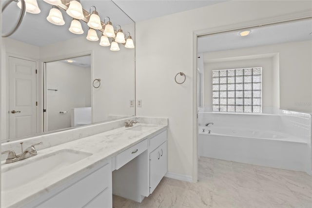 bathroom featuring double vanity, a bath, marble finish floor, and a sink