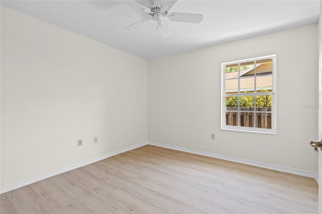 spare room featuring ceiling fan, baseboards, and light wood-style flooring