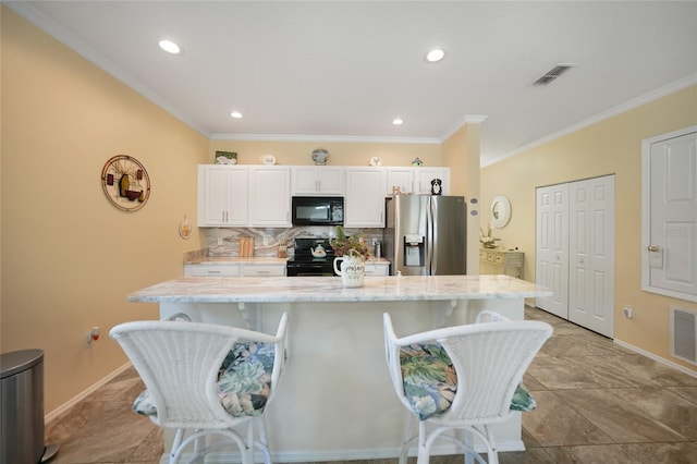 kitchen featuring a kitchen bar, black appliances, decorative backsplash, and visible vents
