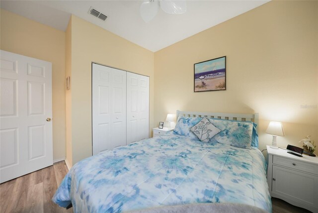 bedroom with a closet, visible vents, a ceiling fan, and wood finished floors