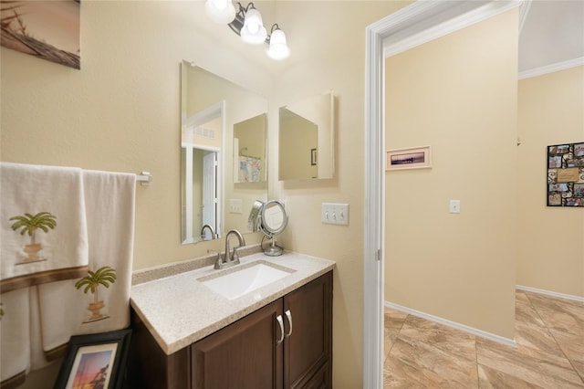 bathroom with vanity, crown molding, and baseboards