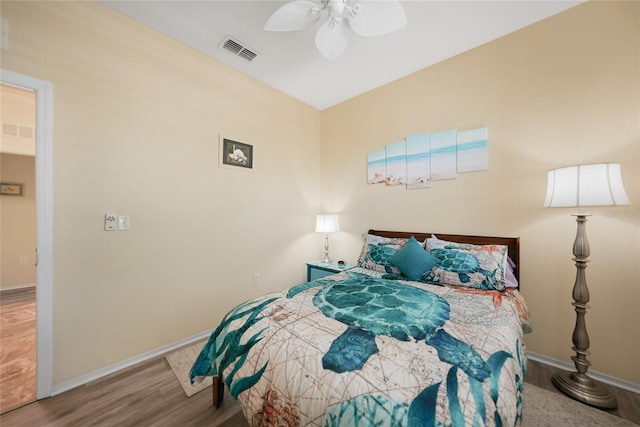 bedroom featuring a ceiling fan, wood finished floors, visible vents, and baseboards