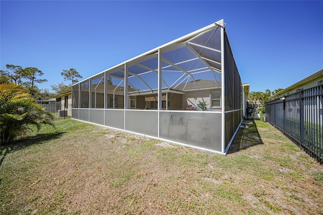 rear view of house with a lanai, fence, and a lawn