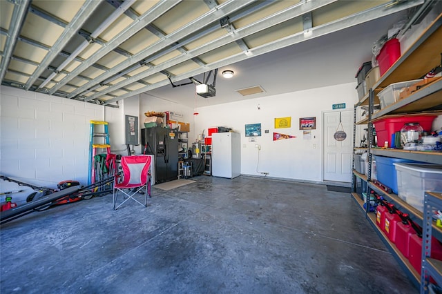 garage featuring black fridge with ice dispenser, a garage door opener, and freestanding refrigerator