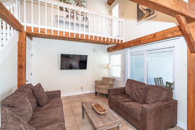 tiled living area with stairway, baseboards, and a high ceiling