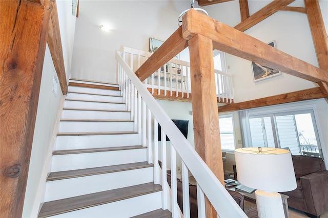 stairs featuring beamed ceiling and a towering ceiling