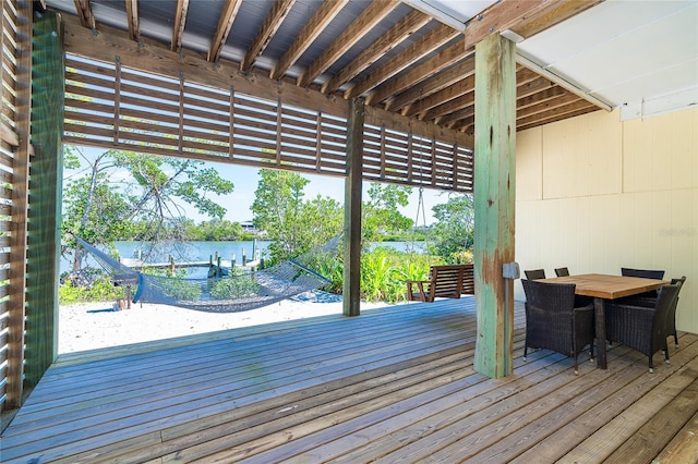 wooden terrace featuring outdoor dining space and a water view