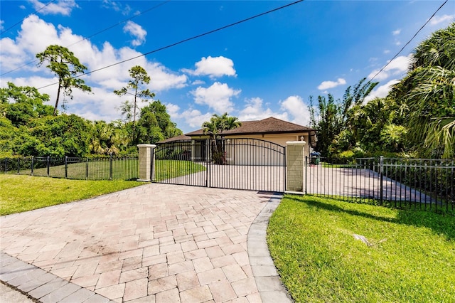 exterior space with a front yard, a gate, an attached garage, a fenced front yard, and decorative driveway