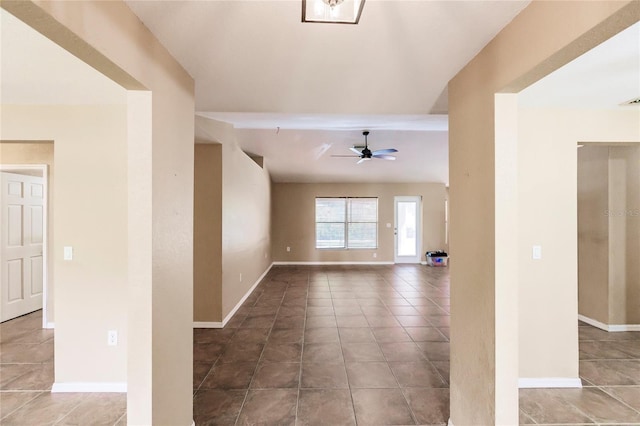 tiled spare room with visible vents, baseboards, and a ceiling fan