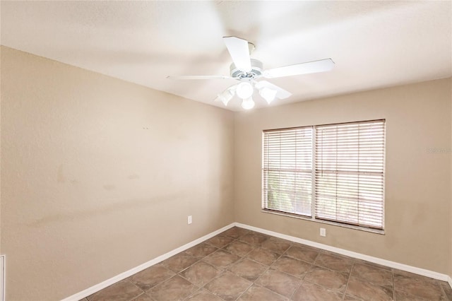 tiled empty room with baseboards and a ceiling fan