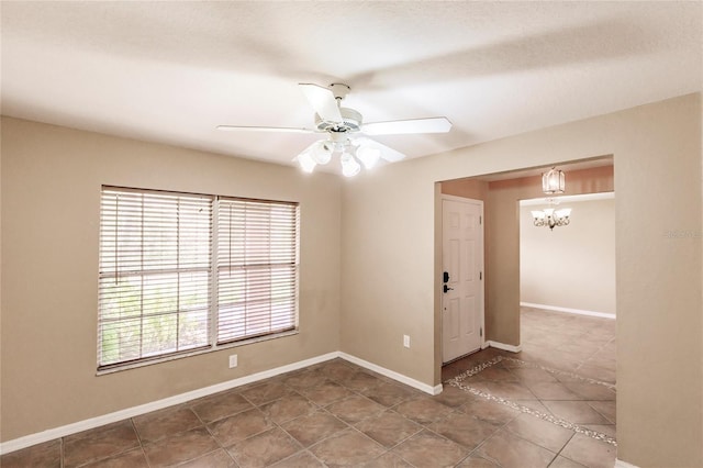 unfurnished room with tile patterned flooring, ceiling fan with notable chandelier, and baseboards