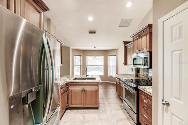 kitchen featuring visible vents, a sink, appliances with stainless steel finishes, a peninsula, and light stone countertops