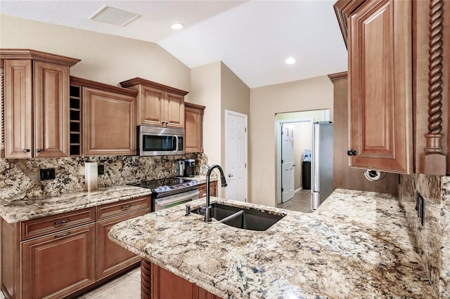 kitchen with light stone countertops, visible vents, lofted ceiling, a sink, and appliances with stainless steel finishes