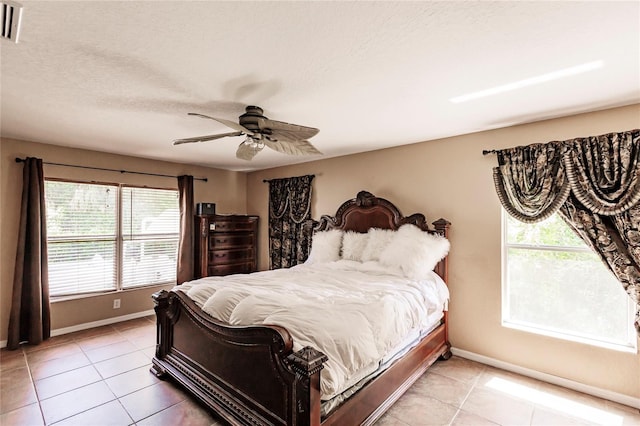 bedroom featuring light tile patterned flooring, ceiling fan, a textured ceiling, and baseboards