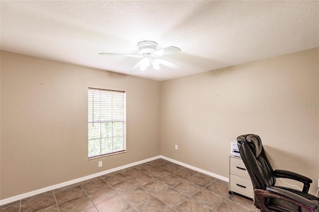 unfurnished office with a ceiling fan and baseboards