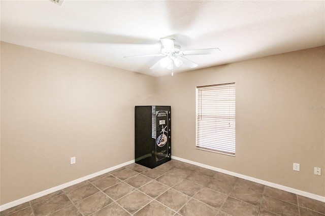 tiled spare room with baseboards and ceiling fan