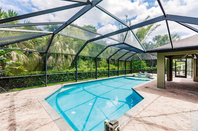 view of pool with glass enclosure, a patio area, and a pool with connected hot tub