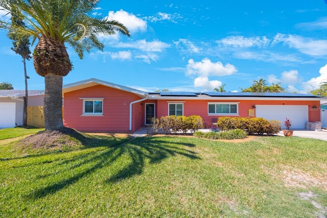 ranch-style house featuring solar panels, a front lawn, an attached garage, and concrete driveway