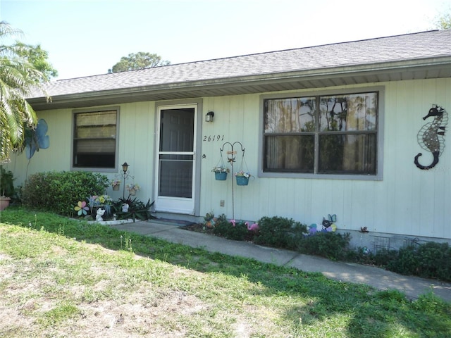 view of front facade with a shingled roof and a front lawn