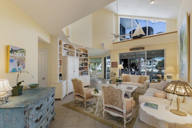 living area with built in features, light tile patterned floors, visible vents, a high ceiling, and ceiling fan