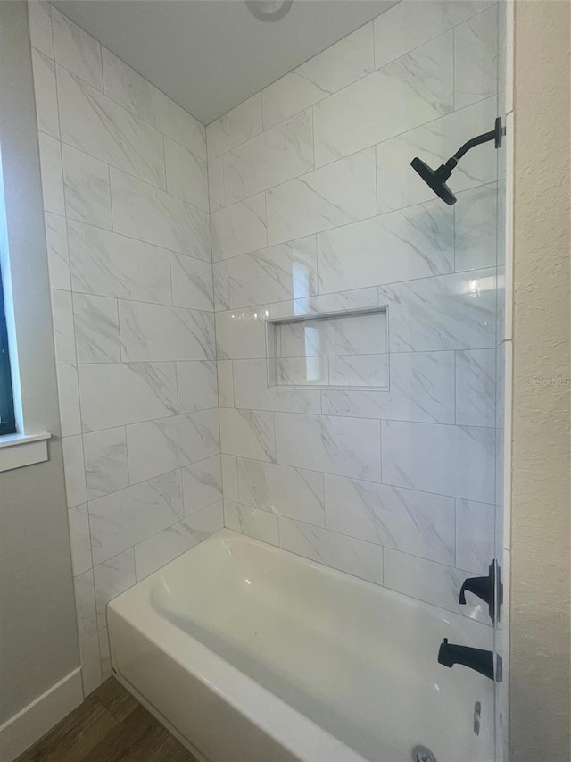 bathroom with shower / bath combination, baseboards, and wood finished floors